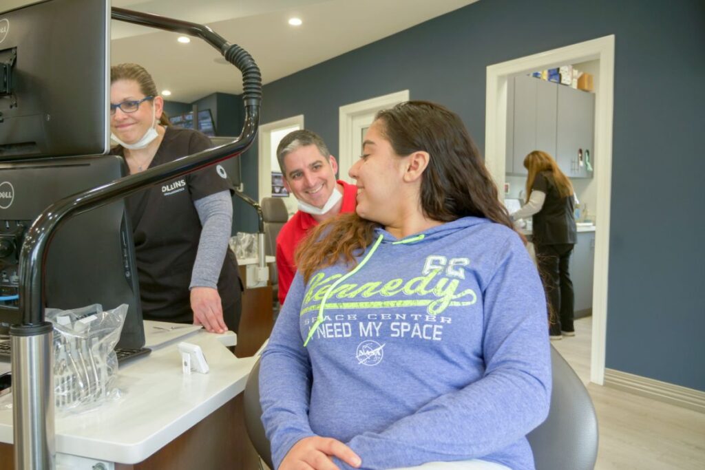 Smiling teen patient in the treatment chair talking with the Ollins Orthodontics team in the Nutley, NJ office, where Dr. Bruce Ollins and Dr. Gabriel Ollins provide Invisalign treatment